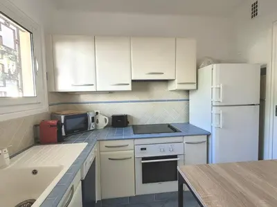 a kitchen with white cabinets and a white refrigerator at La Suite de Saint-Jean-Cap-Ferrat, vue mer et accès mer in Saint-Jean-Cap-Ferrat
