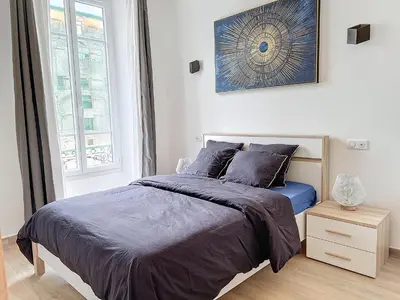 a bedroom with a bed with blue sheets and a window at Central Beautifull Delille Flat in Nice