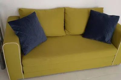 a yellow couch with two blue pillows on it at Studio cosy à Nice in Nice