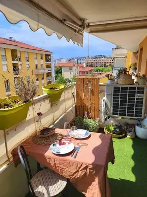 a table on a balcony with a view of a city at Une invitation à la détente in Nice