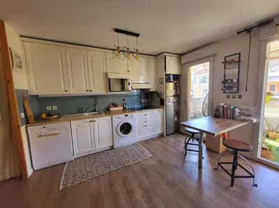 a kitchen with white cabinets and a table in it at Une invitation à la détente in Nice