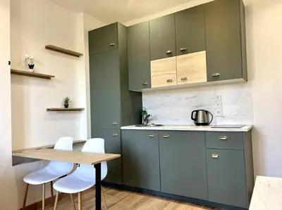 a kitchen with blue cabinets and white chairs and a table at LE RAPHAEL - Studio à 10 min de la mer - Wifi et Climatisation in Nice