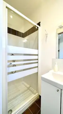 a white bathroom with a shower and a sink at LE RAPHAEL - Studio à 10 min de la mer - Wifi et Climatisation in Nice