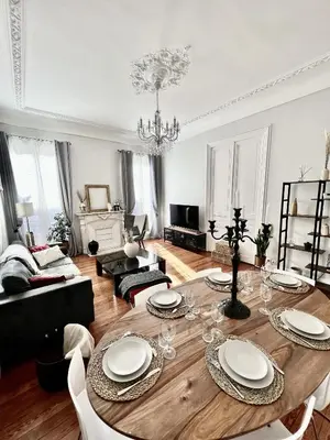 a living room with a wooden table with white plates on it at Superbe Appartement de 105 m2, hyper centre avec Terrasse, parking, à 5 min de la mer in Nice
