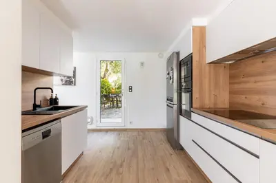 a kitchen with white cabinets and a wooden floor at Villa Summertime in Nice