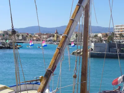 a sail boat in the water with people swimming in the water at Apartment Le Lagon Bleu by Interhome in Cagnes-sur-Mer