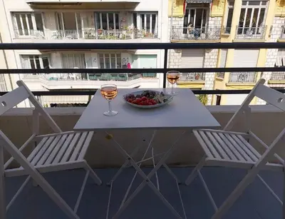 a table with two chairs and a bowl of fruit and wine glasses at Central Rossini Flat with Balcony in Nice