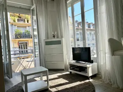 a living room with a tv and a large window at Central Rossini Flat with Balcony in Nice