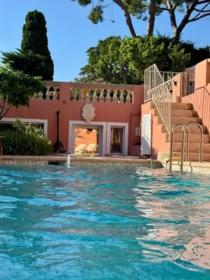 a swimming pool in front of a pink house at Chambre d'hôtes A l'ancre marine de la Villa Rose in Nice