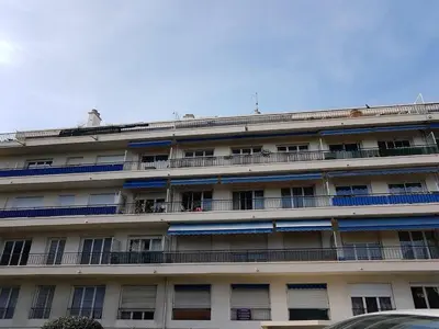 an apartment building with blue balconies and a car at Grand appartement proche Promenade in Nice