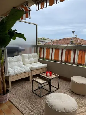 a living room with a couch and a table on a balcony at Grand 2 pièces à 4mns de la plage in Cagnes-sur-Mer