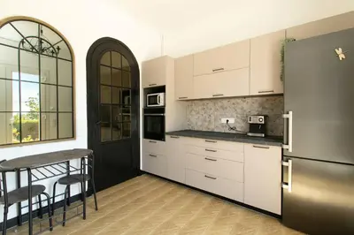 a kitchen with white cabinets and a stainless steel refrigerator at Maison Bianchi - Villa Saint Pierre de Feric in Nice