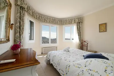 a bedroom with a bed and a table and windows at Maison Bianchi - Villa Saint Pierre de Feric in Nice