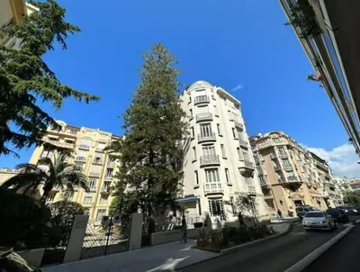 a tall white building with a tree in front of it at Luxueux Appartement 115m2, 3 Chambres centre ville avec parking à 5 min plage -climatisation in Nice