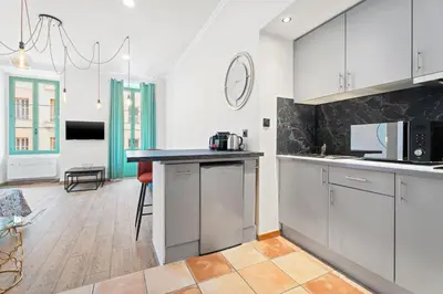 a kitchen with white cabinets and a black counter top at Nice Renting - 2 MASSENA - Luxury Loft - Balcony Massena Square View - AirCon in Nice