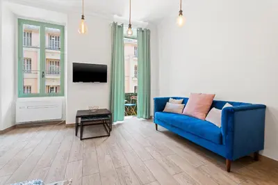 a living room with a blue couch and a tv at Nice Renting - 2 MASSENA - Luxury Loft - Balcony Massena Square View - AirCon in Nice