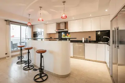a kitchen with white cabinets and bar stools at Chauvain Résidence in Nice