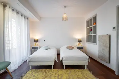 two beds in a room with white walls and a rug at Chauvain Résidence in Nice