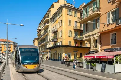 a train traveling down a city street with buildings at Residence Massena in Nice