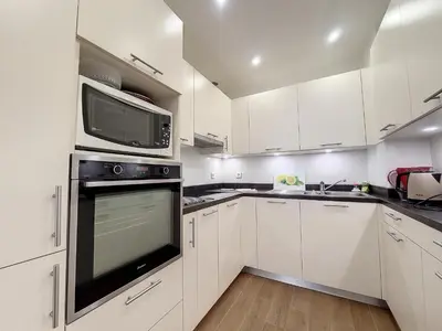 a kitchen with white cabinets and a microwave above a oven at Nestor&Jeeves - BEAUSOLEIL - Central - tres proche mer in Nice