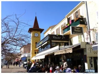 a crowd of people walking down a street with a clock tower at Front sea Luxury in Cagnes-sur-Mer