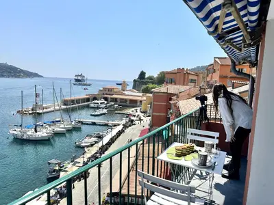 a woman standing on a balcony looking at a marina at MAISON BLEUE AP4362 By Riviera Holiday Homes in Villefranche-sur-Mer