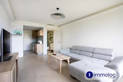 a living room with a gray couch and a table at Air-conditioned studio 5 minutes from the beach and shops in Cros-de-Cagnes
