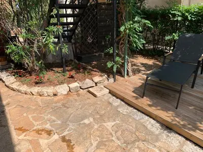 a chair sitting on a wooden deck in a garden at Appartement 1pièce avec jardin dans Mas de Caractère in Saint-Laurent-du-Var