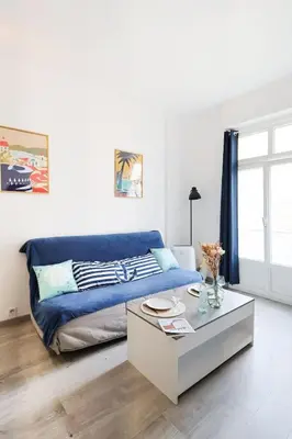 a living room with a blue couch and a coffee table at Appartement 2 pieces in Nice