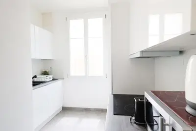 a white kitchen with white cabinets and a window at Appartement 2 pieces in Nice