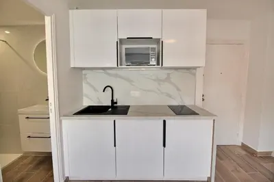 a white kitchen with a sink and a microwave at Cosy appartement en plein coeur de la libération in Nice