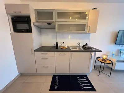 a small kitchen with white cabinets and a sink at Charmant apt calme - proche plage et aéroport - climatisé - parking privé gratuit in Cagnes-sur-Mer