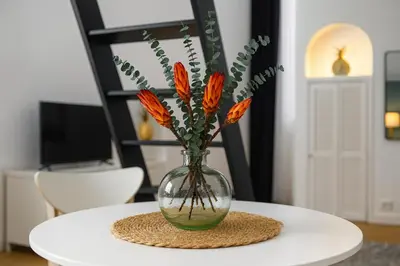 a vase with flowers in it sitting on a table at Studio élégant 4 couchages Front de Mer clim Parking privatif Wifi in Nice