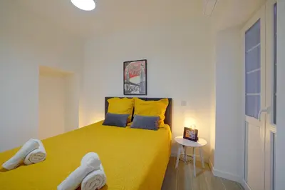 a bedroom with a yellow bed with towels on it at Maison Bianchi - Jaures Old Town in Nice