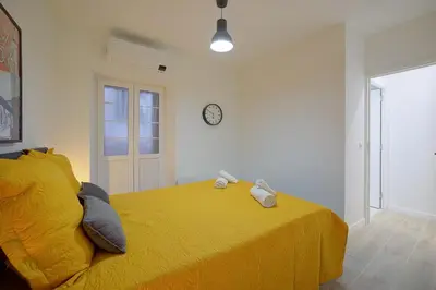 a bedroom with a yellow bed with a clock on the wall at Maison Bianchi - Jaures Old Town in Nice