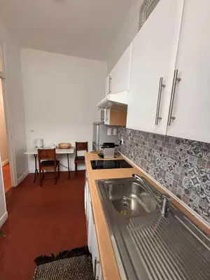 a kitchen with white cabinets and a stainless steel sink at Studio Au coeur de Nice in Nice