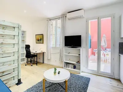 a white living room with a table and a tv at Appartement Terrasse Proche Port et Plages de Nice in Nice