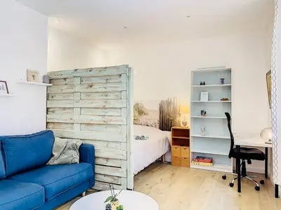 a living room with a blue couch and a bedroom at Appartement Terrasse Proche Port et Plages de Nice in Nice