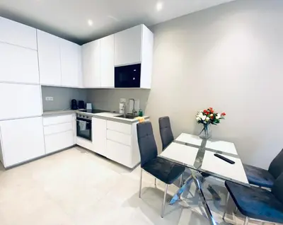 a kitchen with white cabinets and a table and chairs at The entire apartment 2 rooms, Balcony, Sea view in Nice