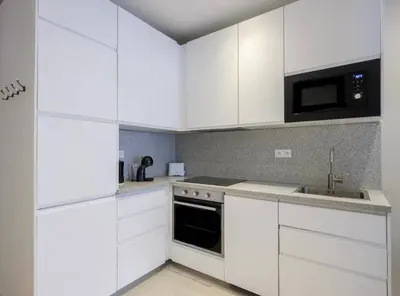 a kitchen with white cabinets and a sink and a microwave at The entire apartment 2 rooms, Balcony, Sea view in Nice