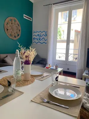 a dining room table with plates and a window at Cosy Blue Nice in Nice