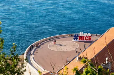 people walking on a sidewalk next to the water at Cosy Blue Nice in Nice
