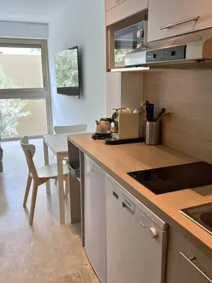 a kitchen with a counter and a table with a chair at Carré d'or Studio 2 in Nice