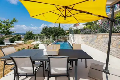 a patio with a black table and a yellow umbrella at Villa Vue Mer, Piscine & Plage à 6Min in Cagnes-sur-Mer