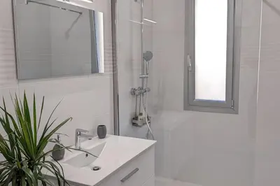 a white bathroom with a sink and a mirror at 3 pièces dans villa avec piscine in Nice