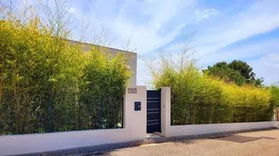 a white fence with a gate in front of a hedge at Studio climatisé vue imprenable wifi in Vence