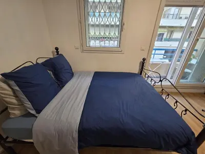 a bedroom with a bed with blue pillows and a window at Aya's Studio in Nice