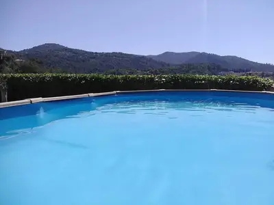 a large blue swimming pool with mountains in the background at VILLA DE CHARME sur la Côte d'Azur in Tourrette-Levens