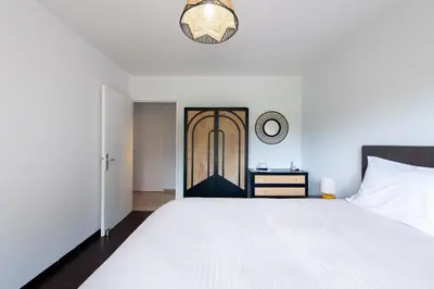 a bedroom with a white bed and a clock on the wall at Happyfew Le Flora in Nice
