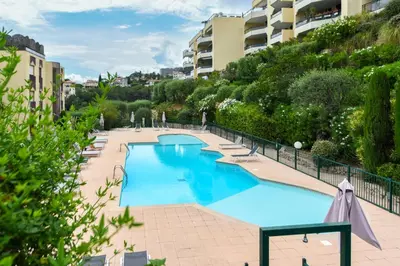a large blue swimming pool with chairs and trees at Happyfew Le Flora in Nice